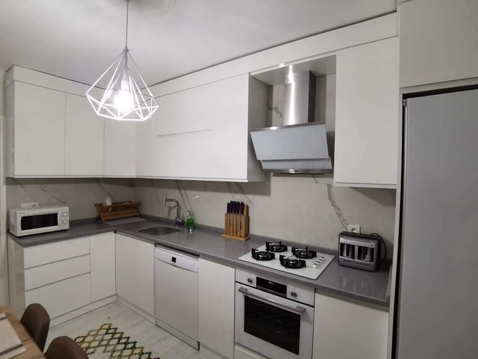 Beyaz dolaplı mutfak, gri tezgah ve ankastre set